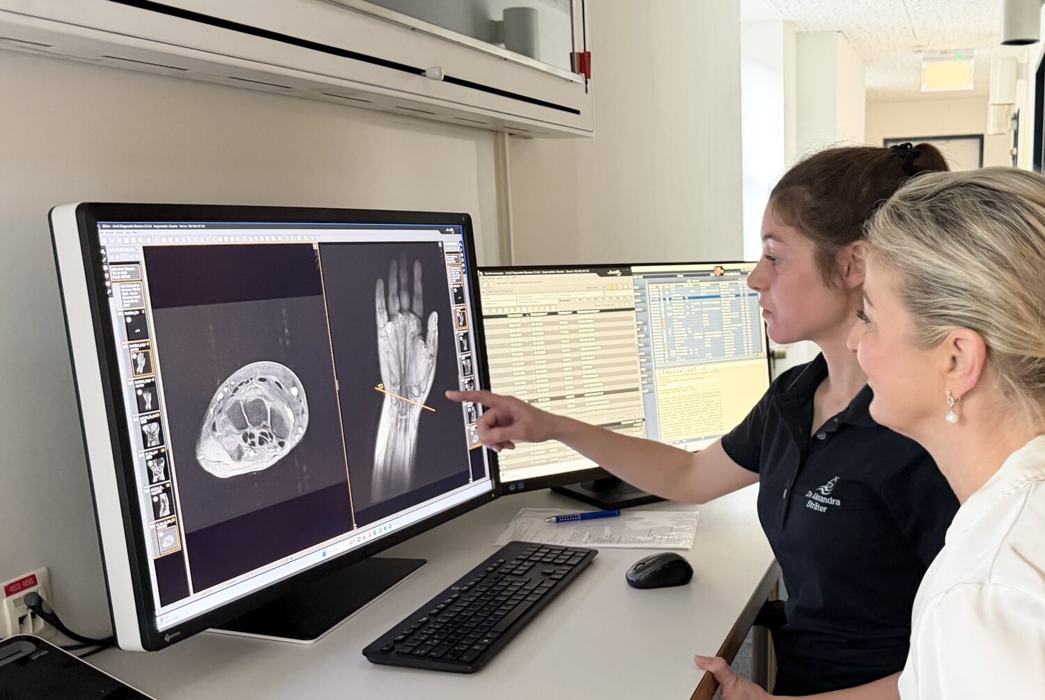 MRT Handgelenk in der Radiologie Mühleninsel. Befundbesprechung vor einem Computer mit Ärztin und Patientin. Auch kleinere Gelenke wie das Handgelenk oder der Ellenbogen lassen sich sehr gut untersuchen. Hier können Bandverletzungen, Sehnenreizungen oder entzündliche Veränderungen präzise beurteilt werden.